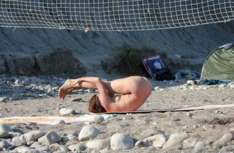 Flexible girl does yoga in the nude while camping out on a beach