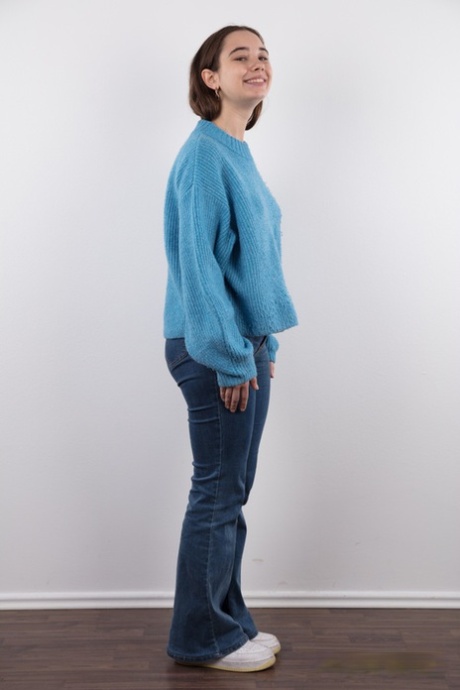 Amateur model Uliana stands naked after removing a sweater and blue jeans