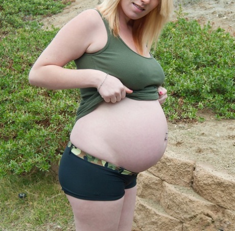 Pregnant girl holds a sex toy while showing her hairless vagina