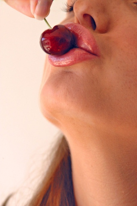 Pretty girl Sandra Shine curls her tongue while sucking juice from a cherry