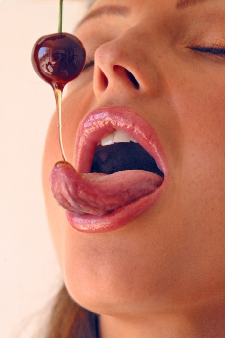 Pretty girl Sandra Shine curls her tongue while sucking juice from a cherry