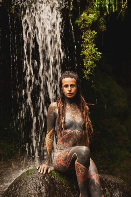 Heavily tattooed lesbians hold each other while totally naked on a bridge