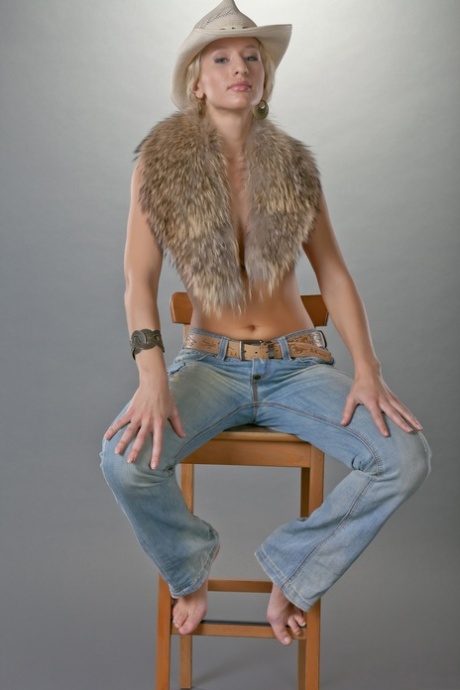 Blonde cowgirl Lera D reveals her small ass and tight muff on a chair
