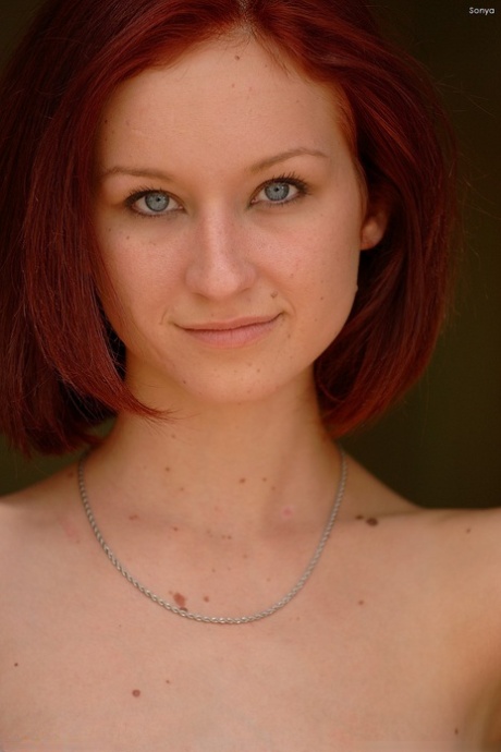 Skinny redhead Sonya poses nude and fingers her juicy pussy on the floor